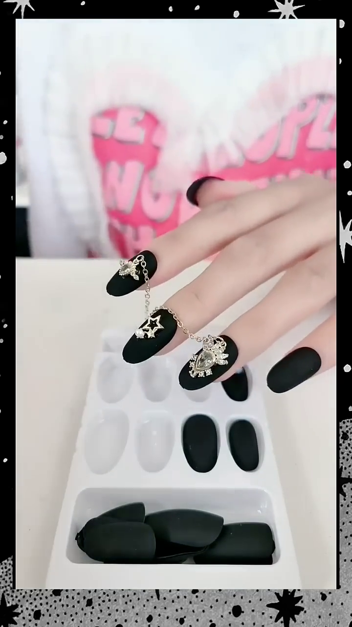 Stunning Black Matte Nails Adorned with Elegant Silver Star and Heart Jewelry Accents – Perfect for a Bold and Fashion-Forward Look