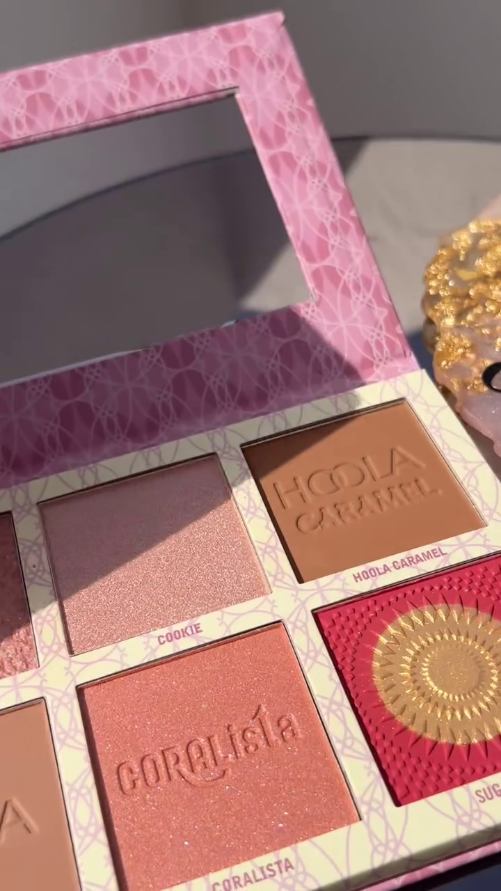 he Hoola Caramel and Coralista Blush Palette by Benefit, Featuring Soft Pink and Caramel Tones with a Touch of Golden Highlighting Shades, Surrounded by a Delicate Pink and Gold Design