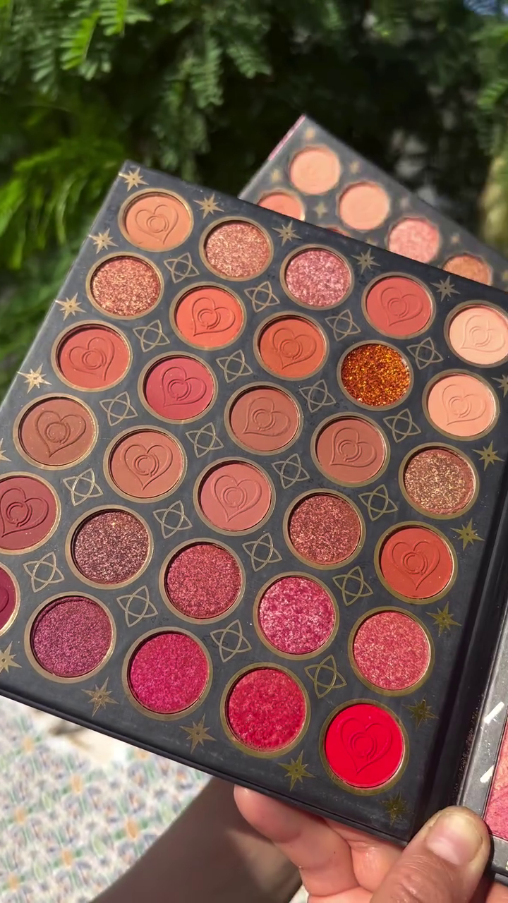 Vibrant and Bold Eyeshadow Palette Featuring a Stunning Array of Red, Pink, and Orange Shades with Glittery and Matte Finishes, Accentuated by Heart and Star Imprints for a Touch of Glamour